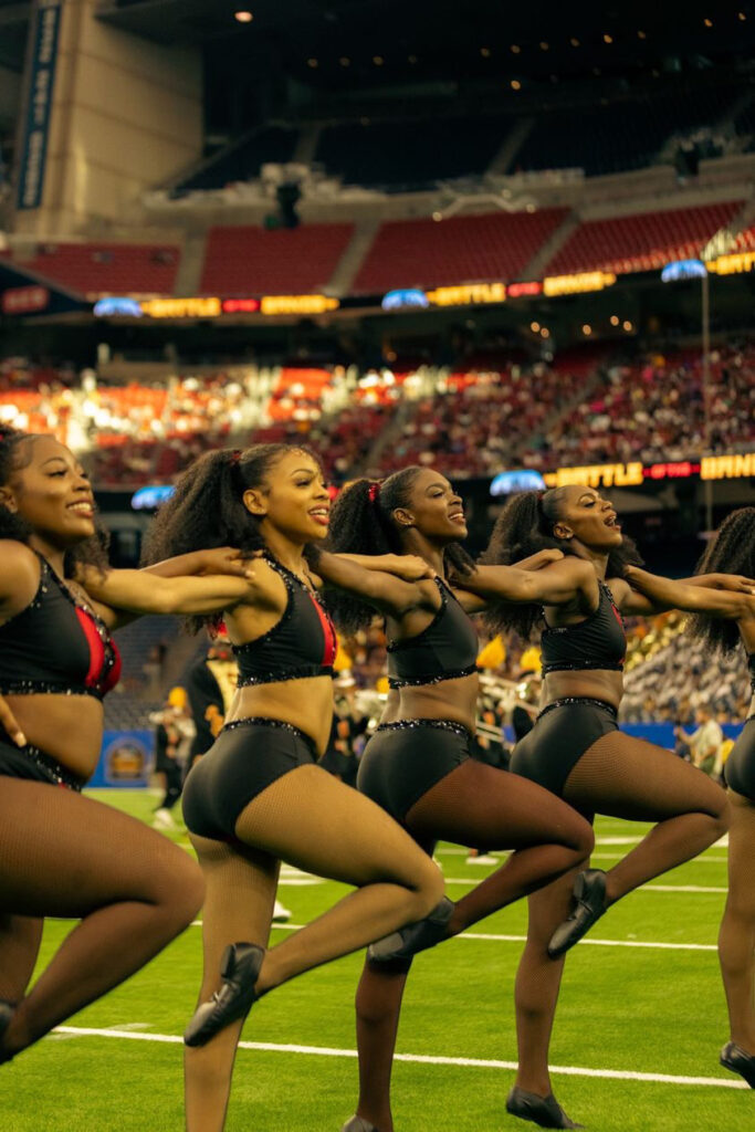 a group of dancers performing a kick line on the football field