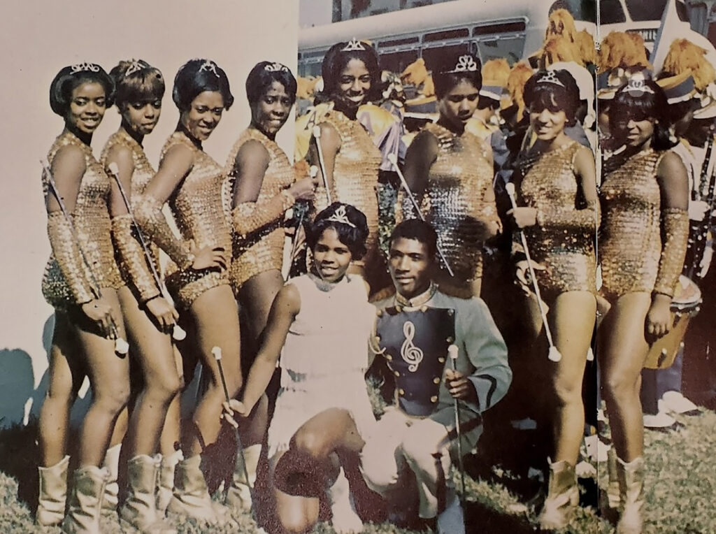 an old photo from the 1960s of dancers in gold uniforms holding batons